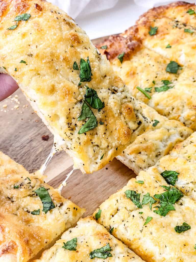 removing a cheesy garlic breadstick from plate