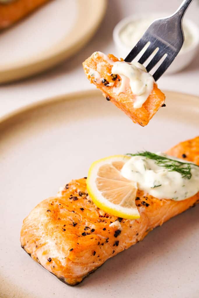fork holding bite of salmon with dill sauce