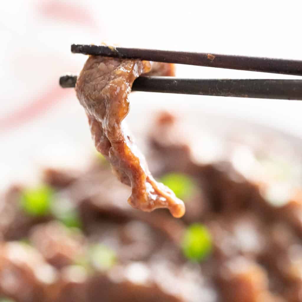 chopsticks holding piece of Mongolian beef