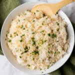 garlic rice in white bowl with wooden spoon