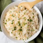 garlic rice in white bowl with wooden spoon
