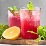 two glasses of passion tea lemonade with mint garnish and lemon half