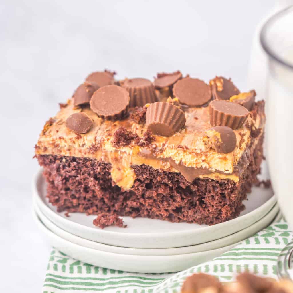 slice of peanut butter poke cake on white plate with green napkin