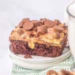 slice of peanut butter poke cake on white plate with green napkin