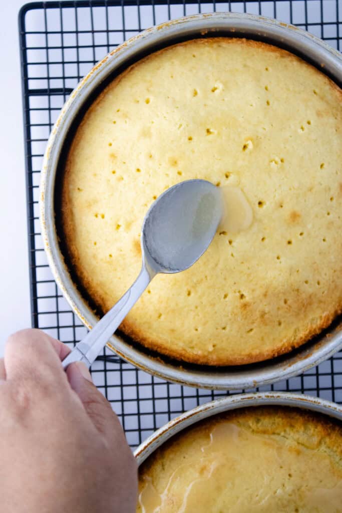 pouring sauce over cake with holes poked in it