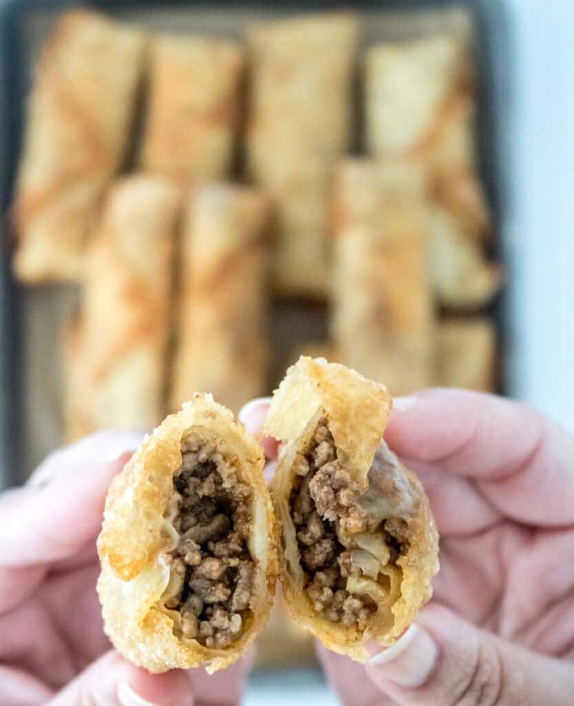 hand holding cheeseburger eggroll cut in half