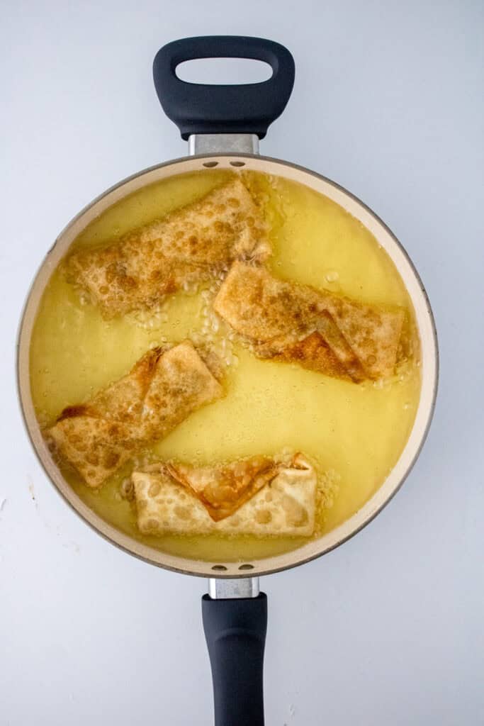 frying cheeseburger eggrolls in oil