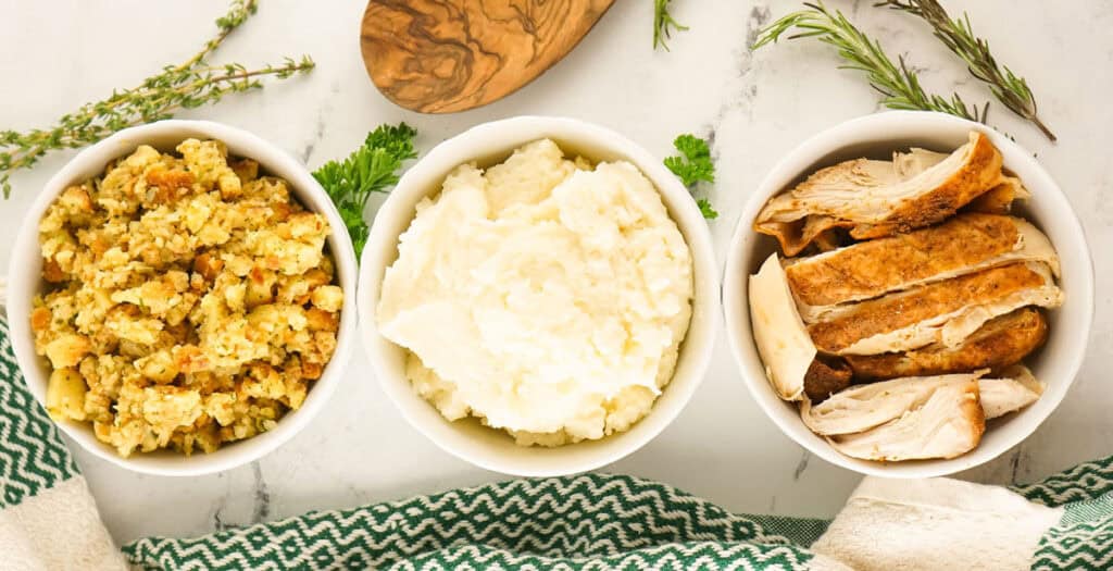 stuffing, turkey, and mashed potatoes in white bowls