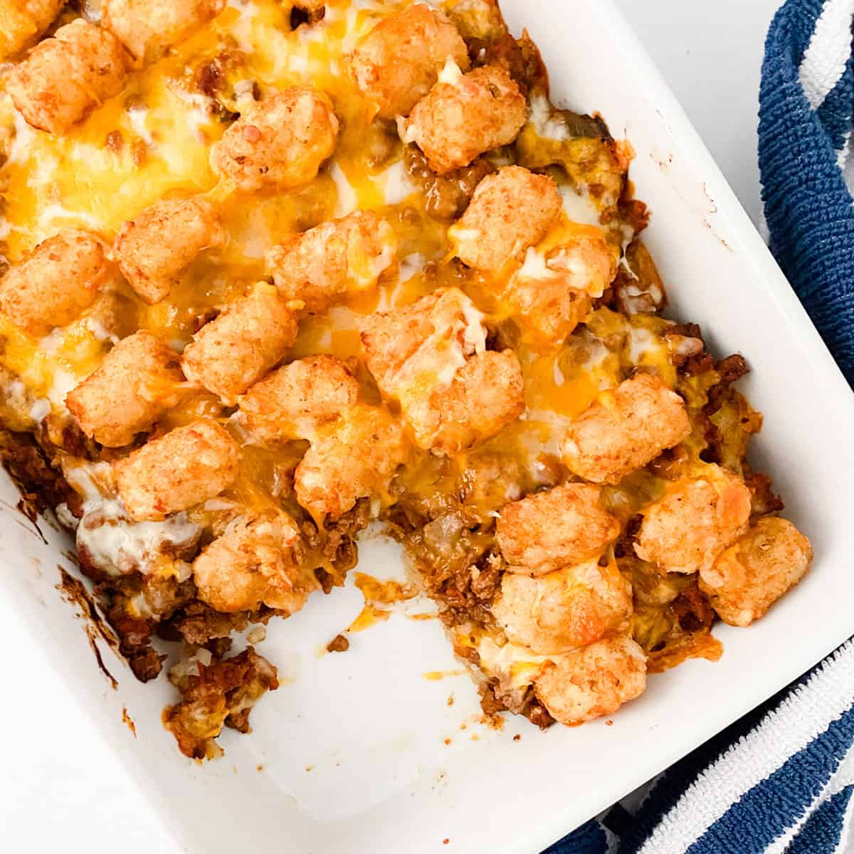 baking dish of taco tot casserole with one serving removed