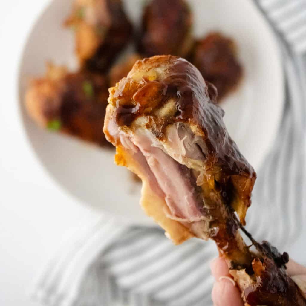 holding a slow cooker barbecue drumstick with bite removed