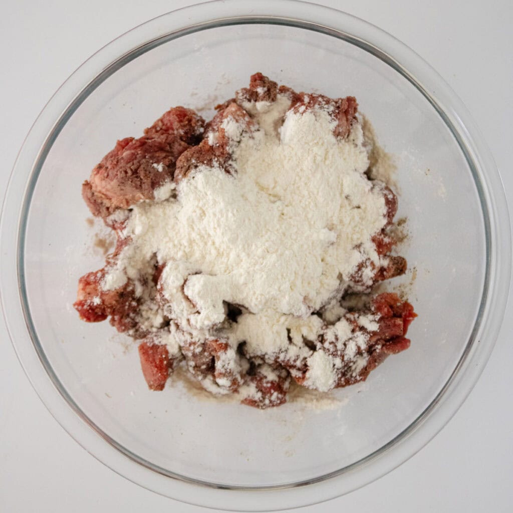 flour over beef tips in bowl