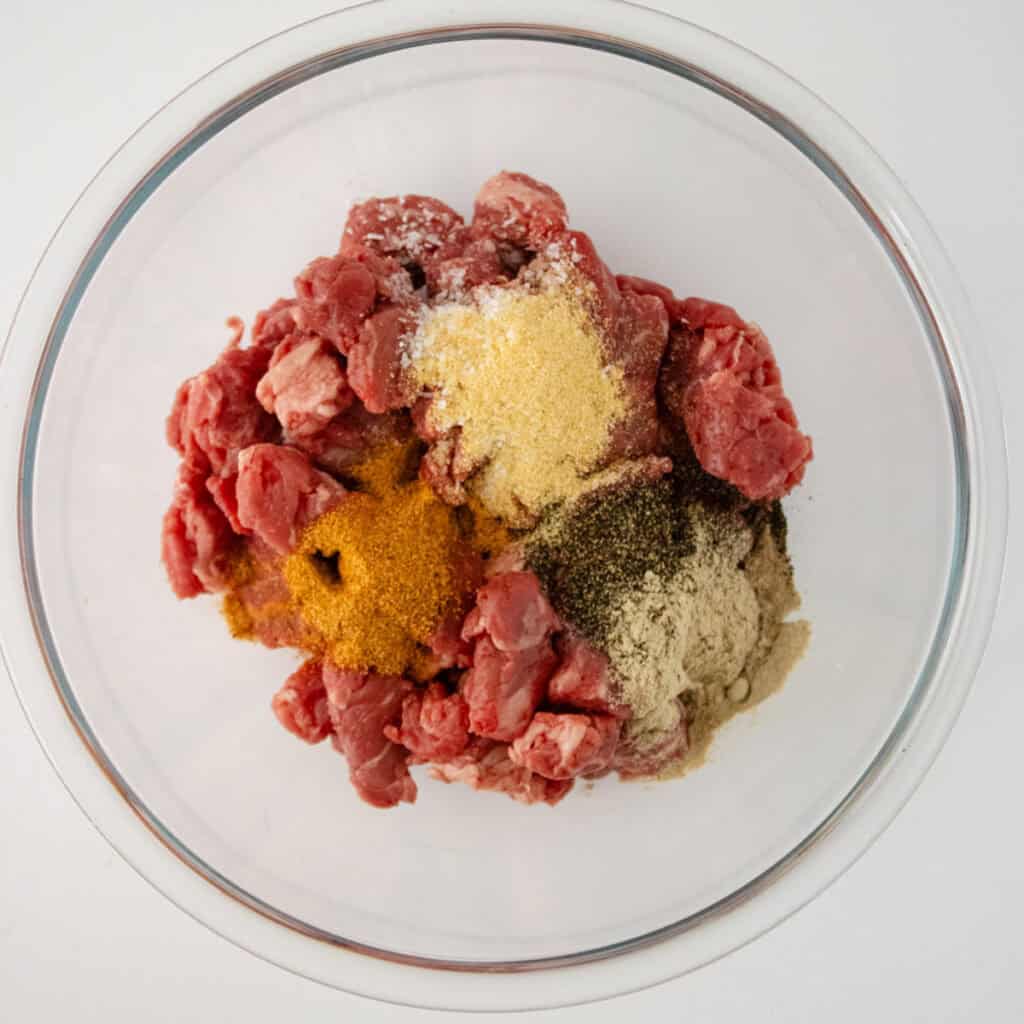 beef tips and seasonings in glass bowl