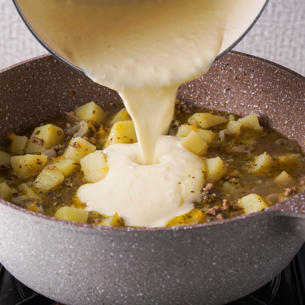 pouring cheese mixture into cheeseburger soup 