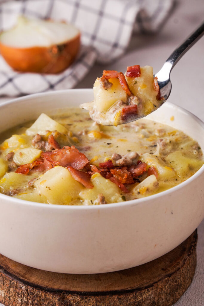 bowl of cheeseburger soup with spoonful held over it