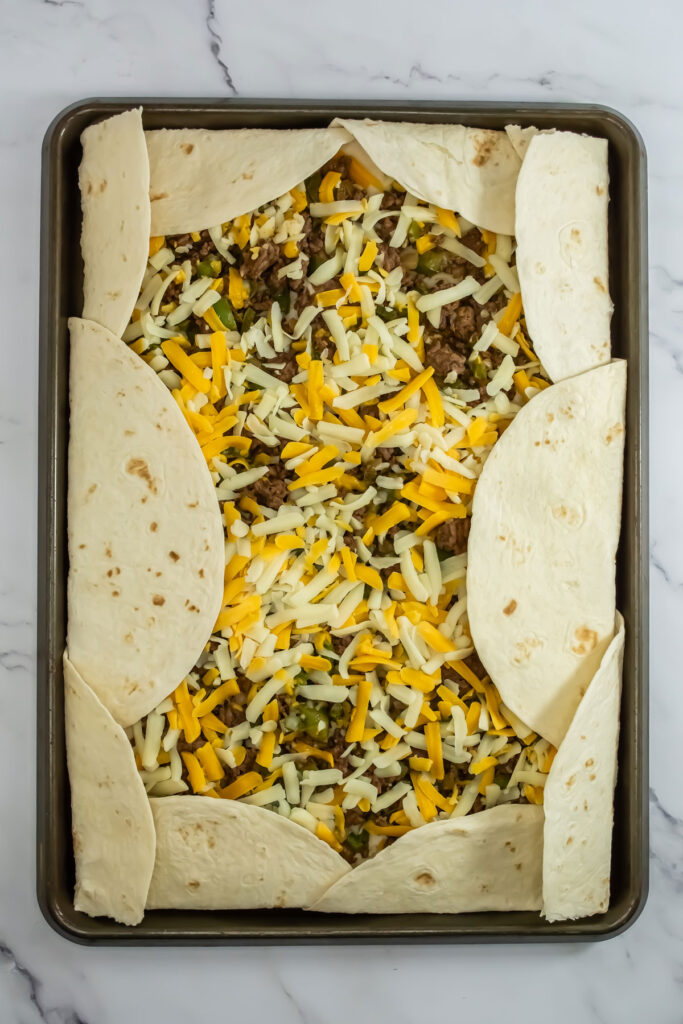 tortillas, ground beef, and cheese on baking sheet