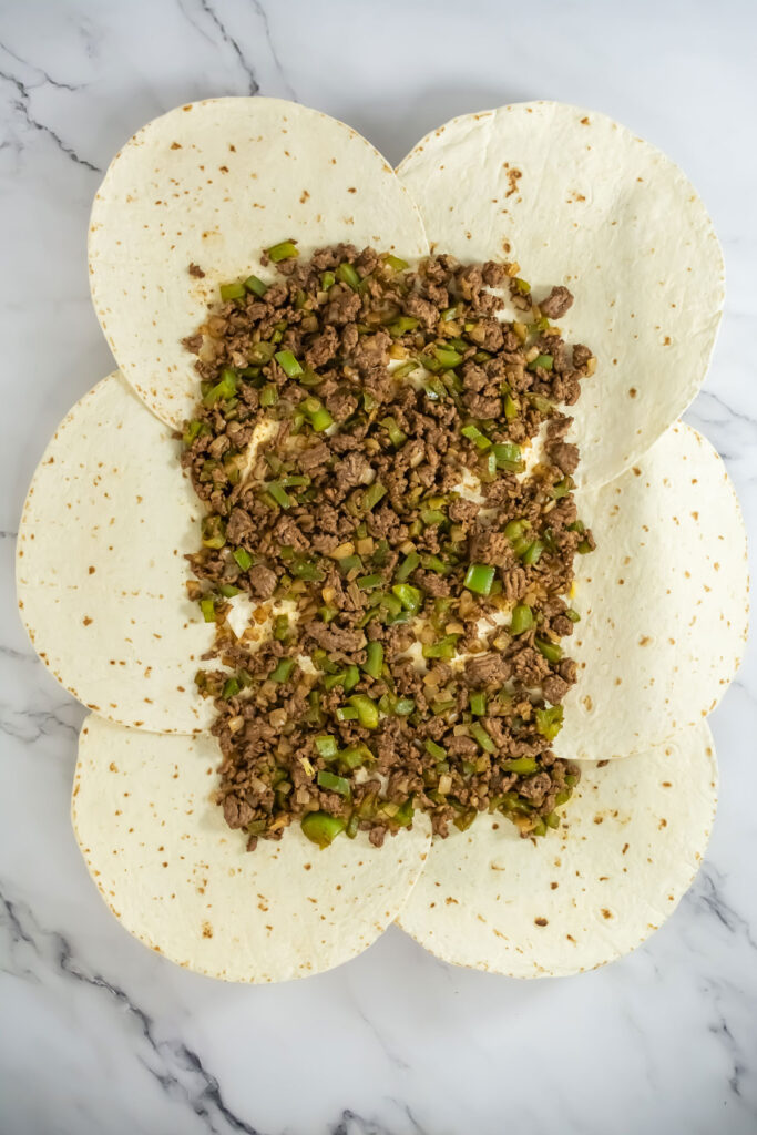 tortillas on baking sheet topped with ground beef