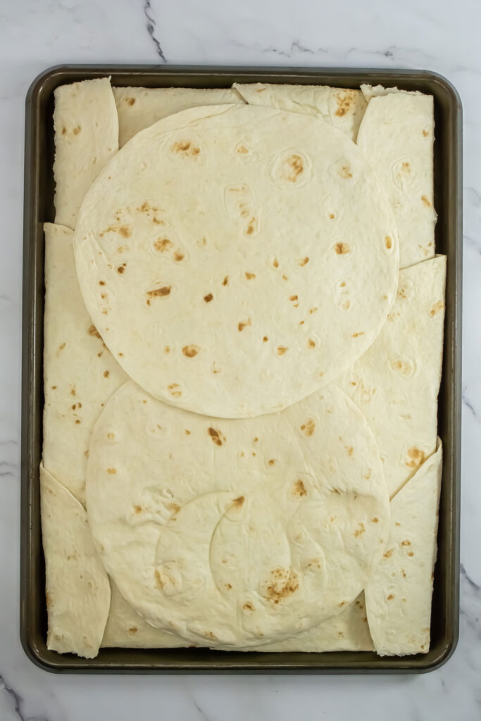tortillas layered on baking sheet