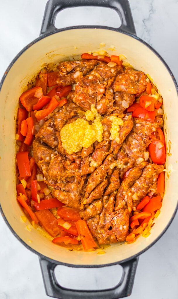 ground meat, sliced red peppers, and garlic in pot