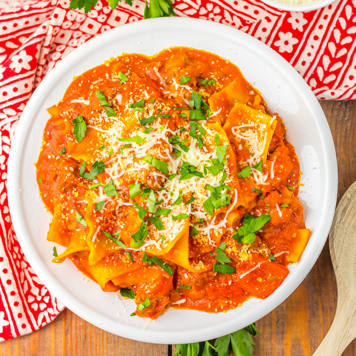 white bowl with spicy lasagna soup and red patterned napkin