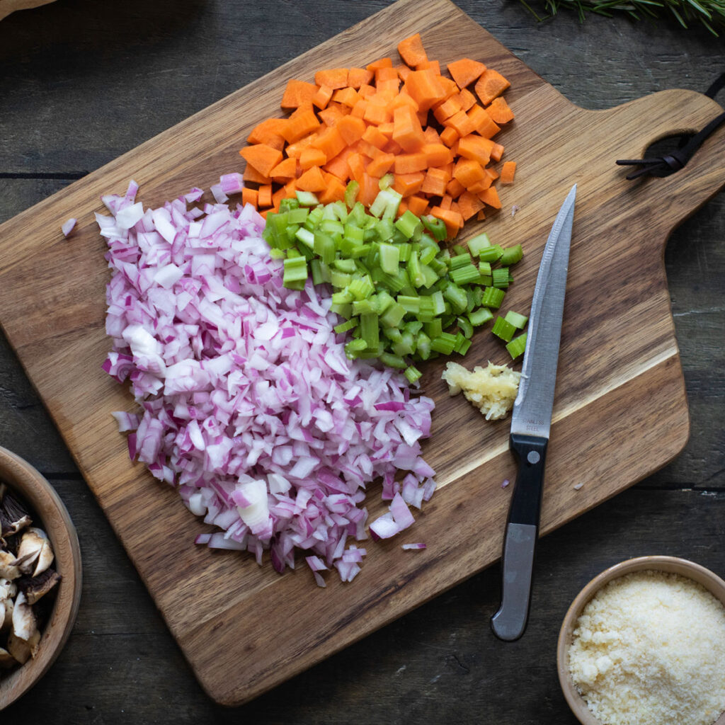 chopped onion, carrots, and celery on cutting board