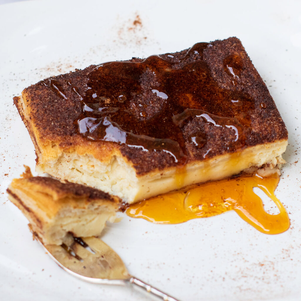 piece of churro cheesecake bars with bite on fork