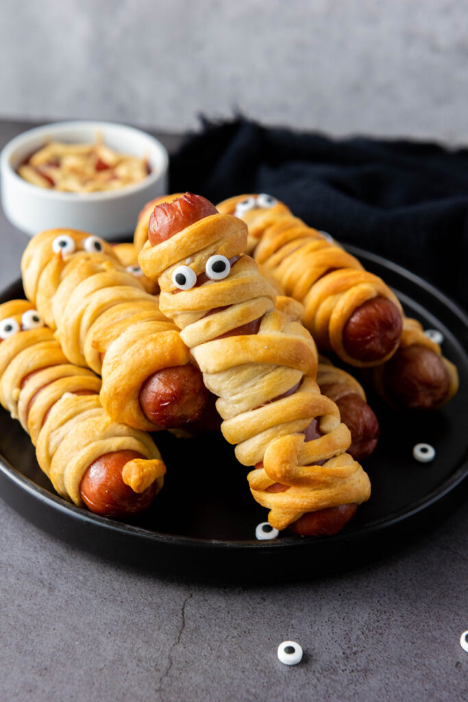 mummy hot dogs on black plate