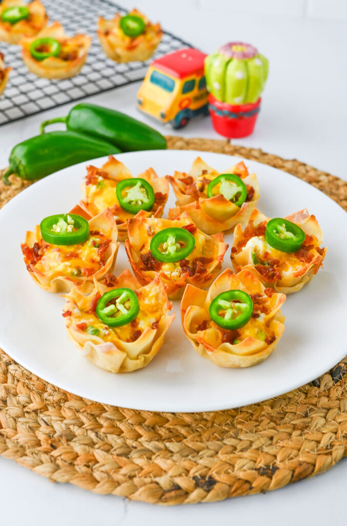 jalapeño popper wontons on white plate with peppers in background