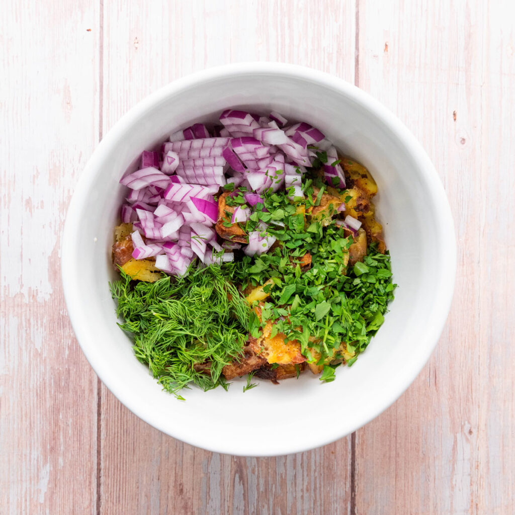 smashed potato salad ingredients in white bowl