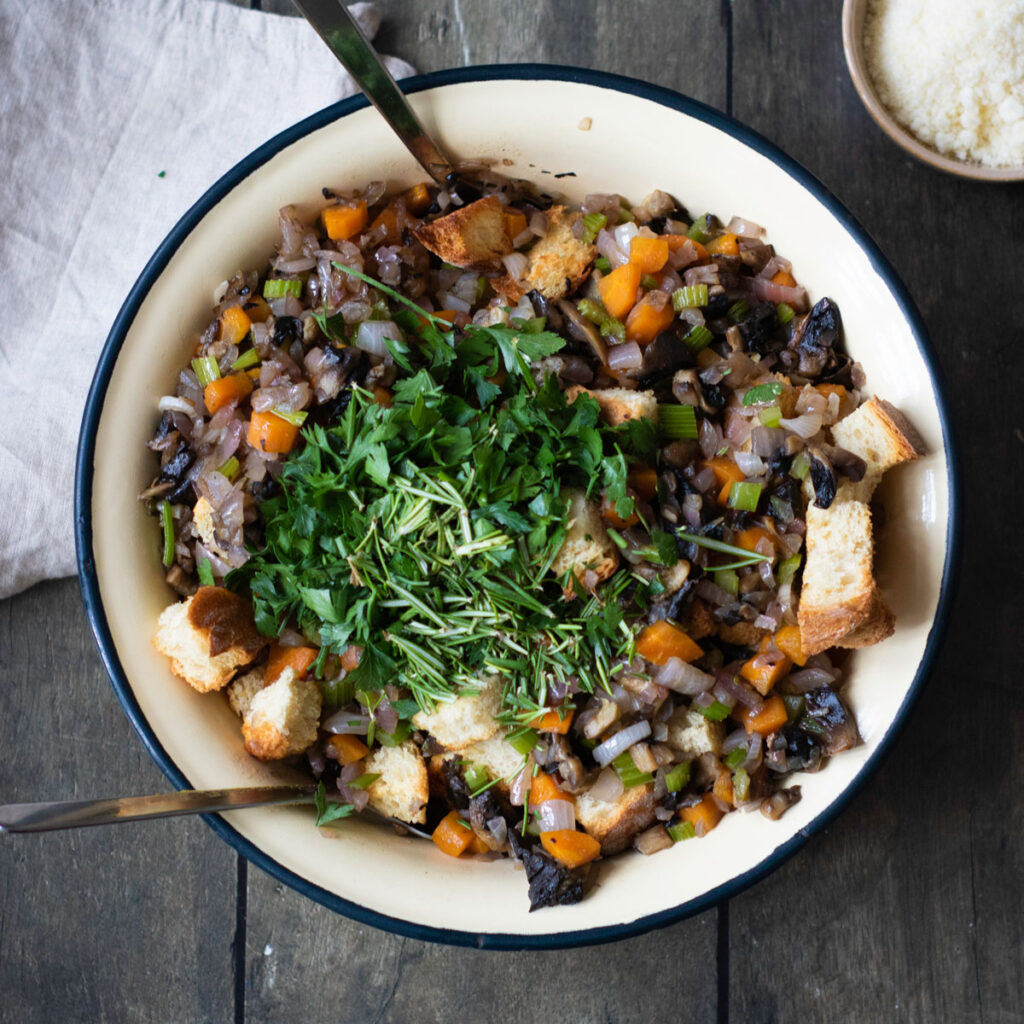 mixing herb stuffing ingredients in white bowl