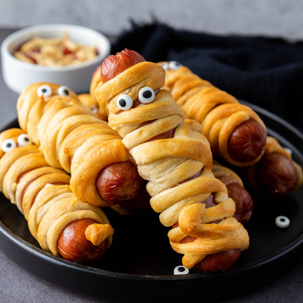 mummy hot dogs on black plate