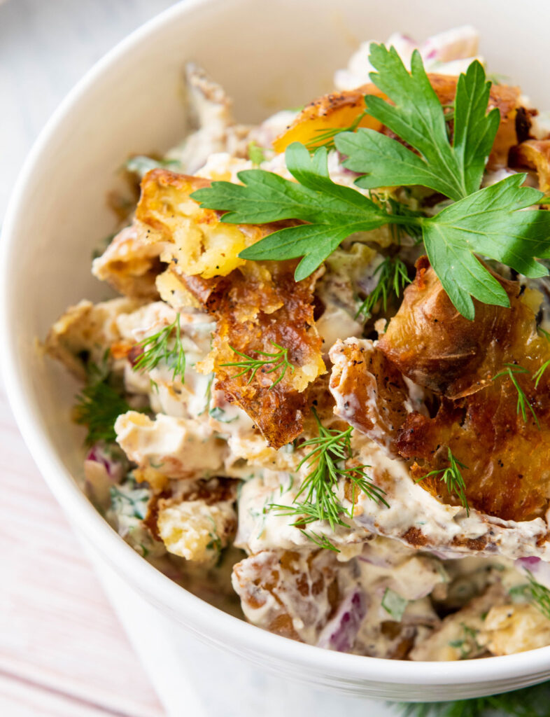 close up of smashed potato salad in white bowl