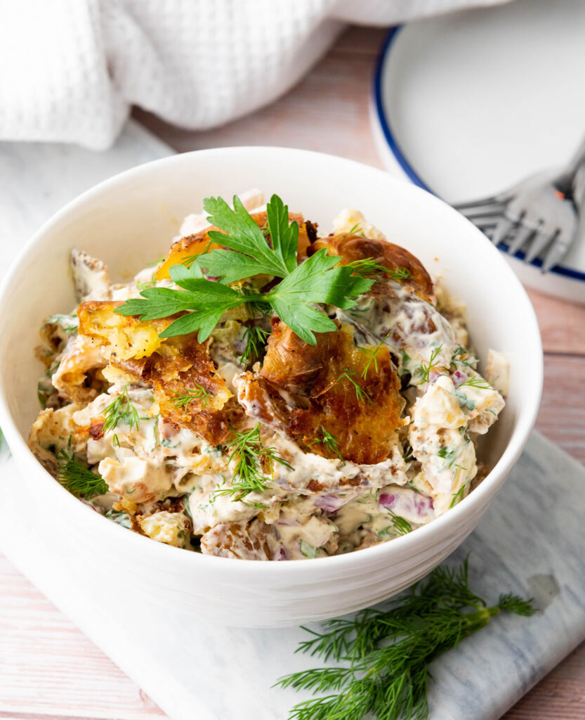 white bowl of smashed potato salad