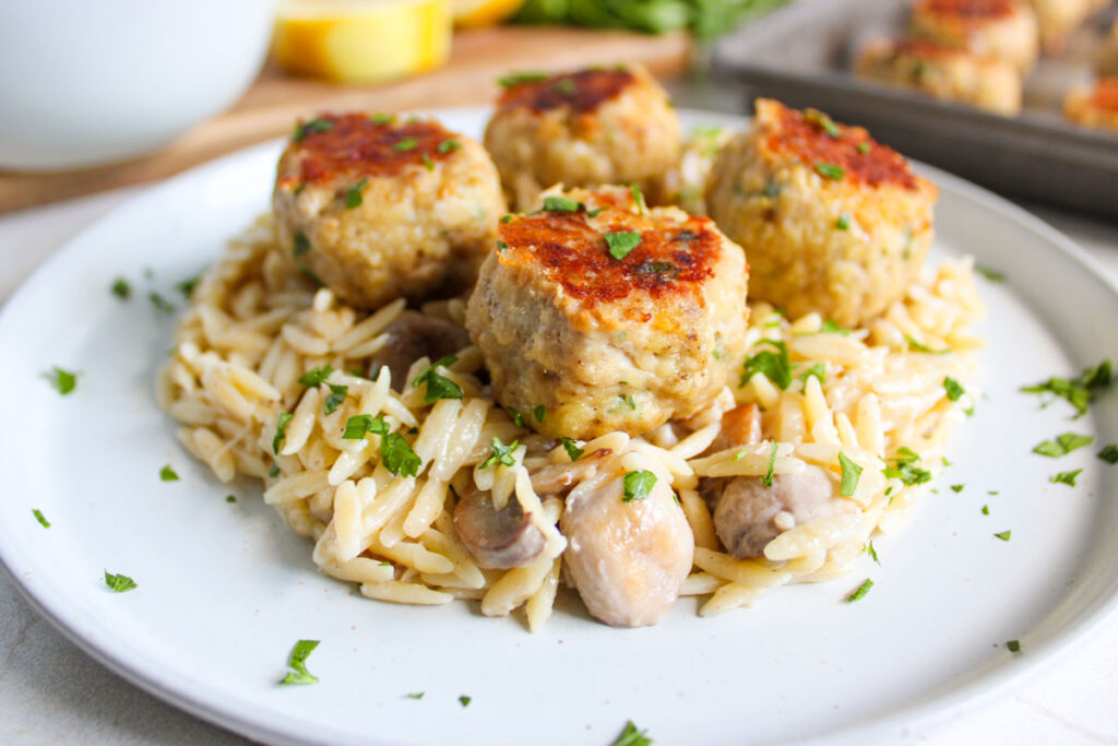 white plate with mushroom orzo and chicken meatballs