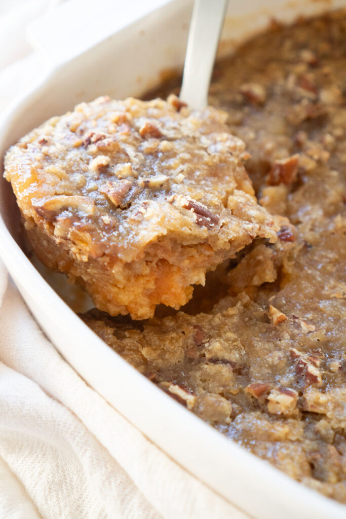 spoon scooping up serving of sweet potato casserole
