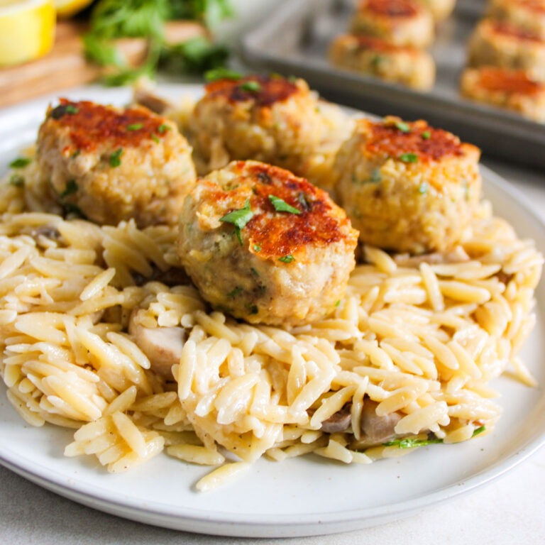 orzo topped with chicken meatballs on white plate