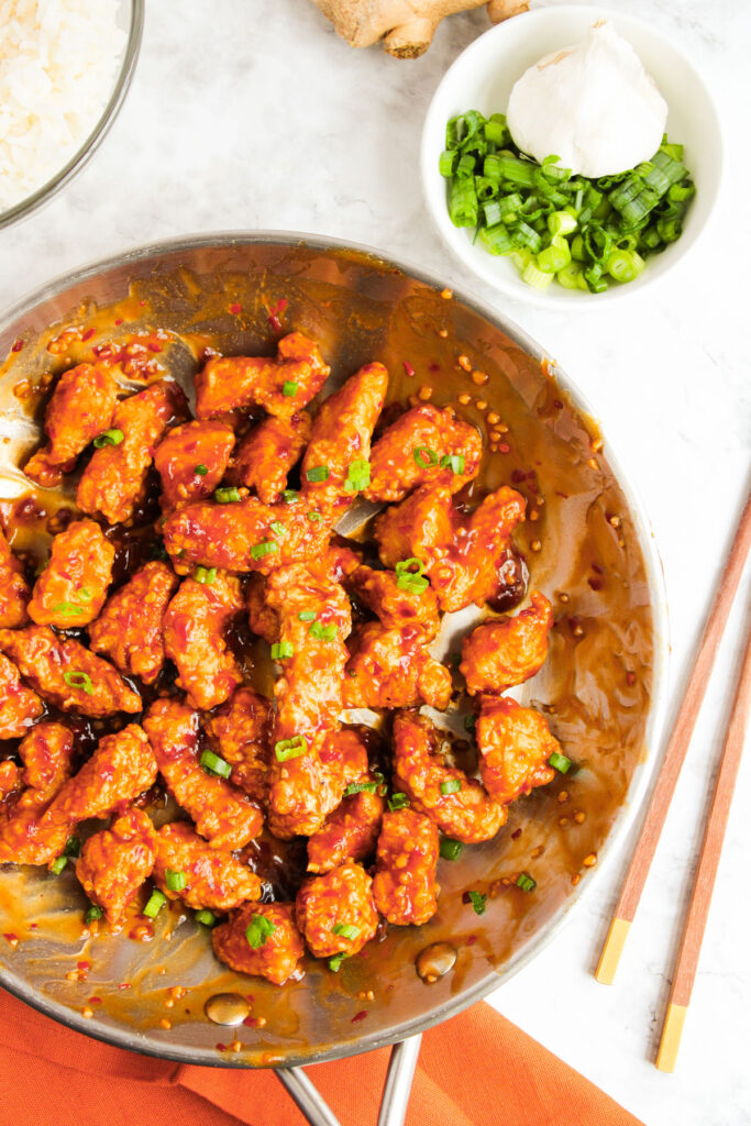 general tsos chicken in skillet with chopsticks nearby