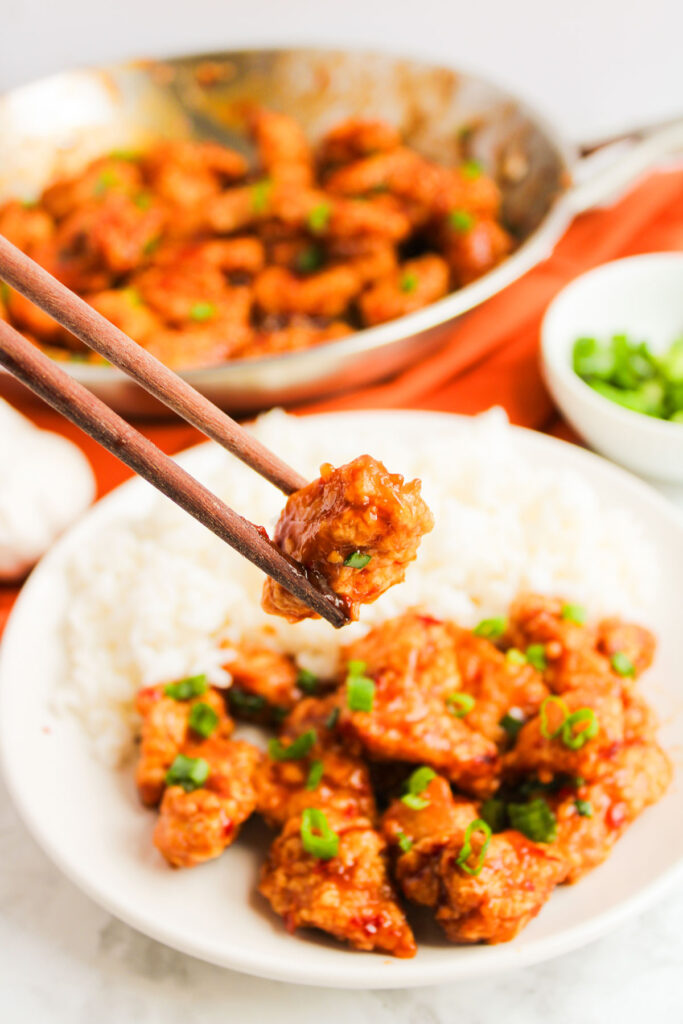 chopsticks holding general tsos chicken piece