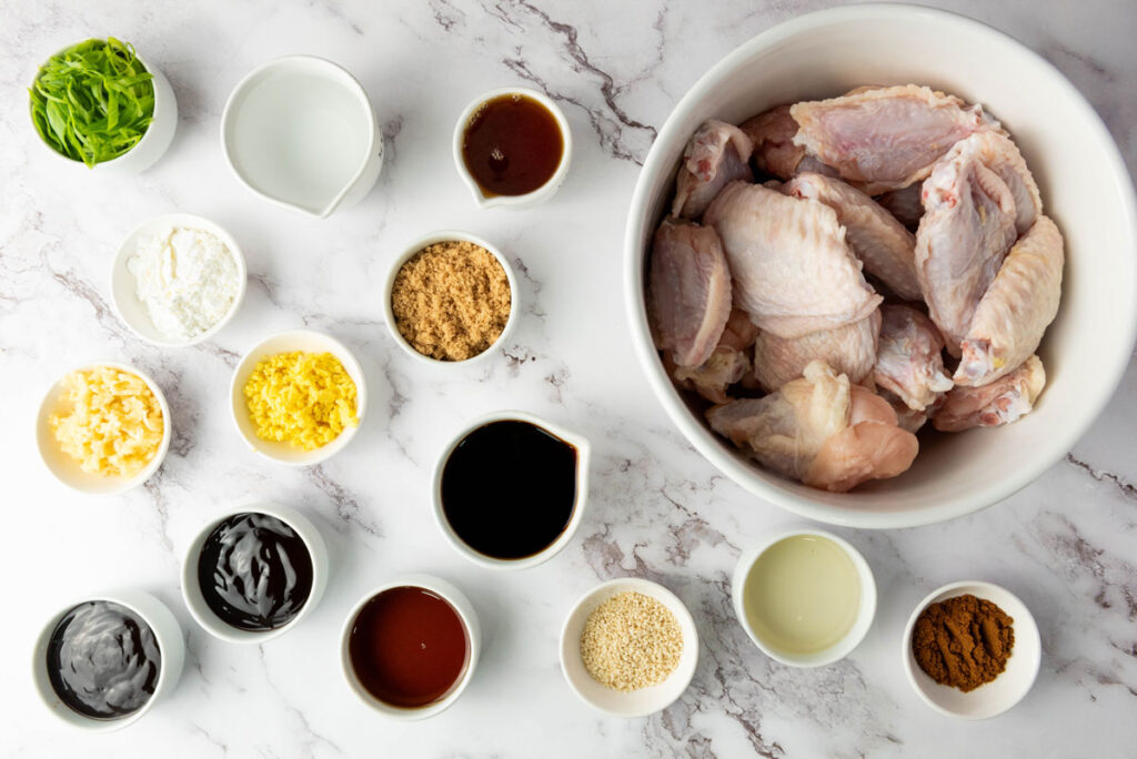 asian sticky wings ingredients in white bowls on marble counter