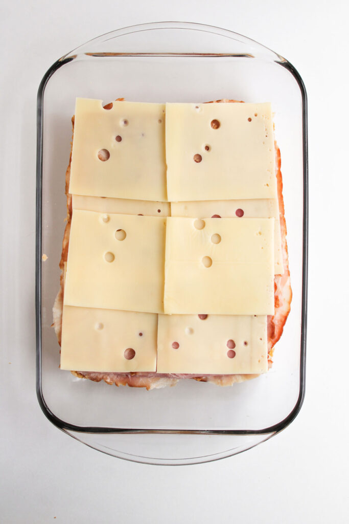 swis cheese on ham and bread in baking dish