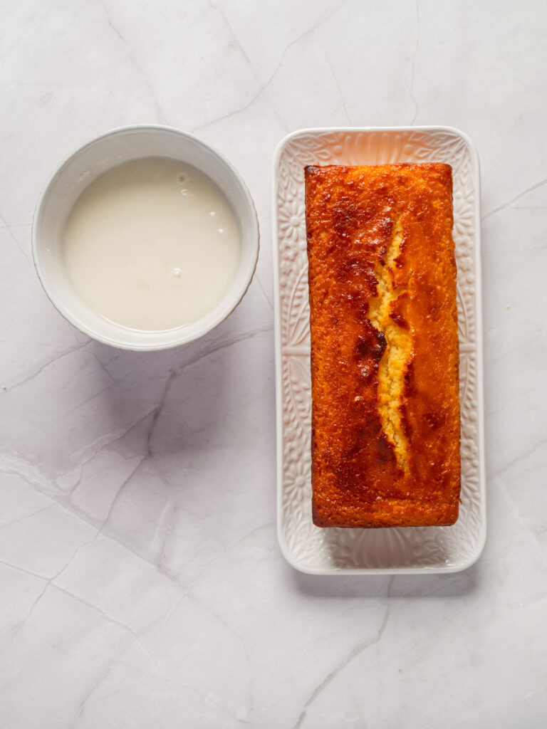 lemon loaf cake with bowl of icing nearby