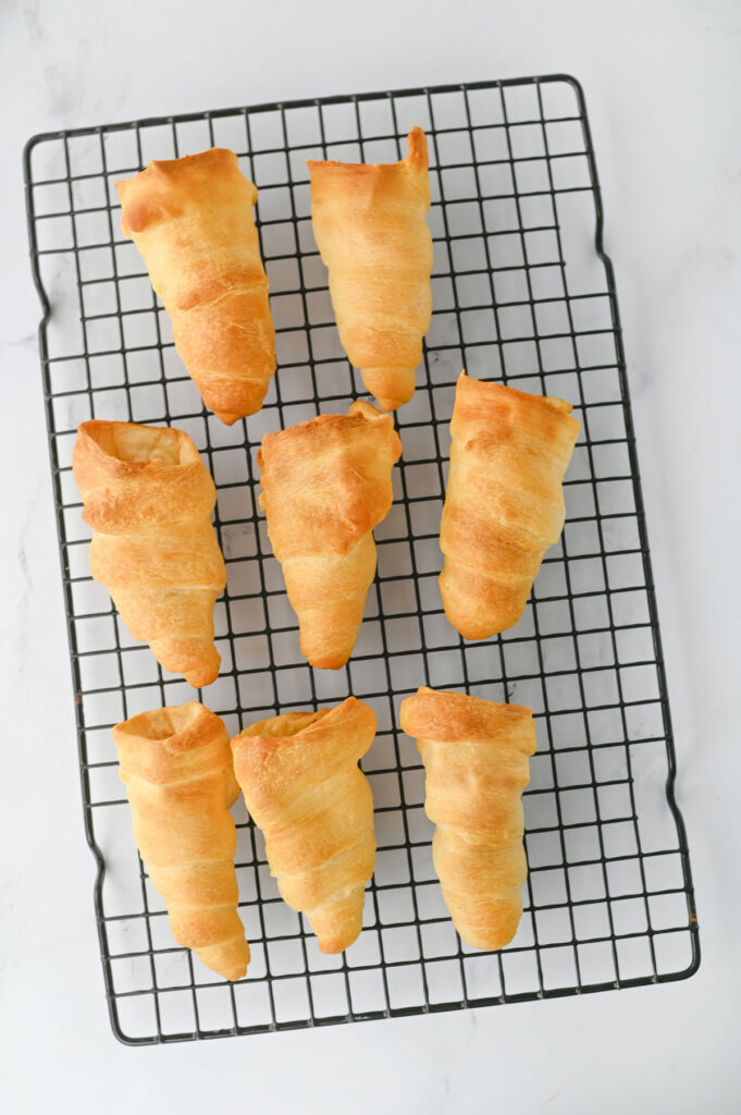 crescent rolls shaped like carrots on wire rack