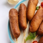 homemade corndogs on white plate with blue rim