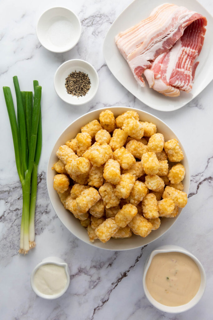 loaded tater tots ingredients in bowls on marble counter
