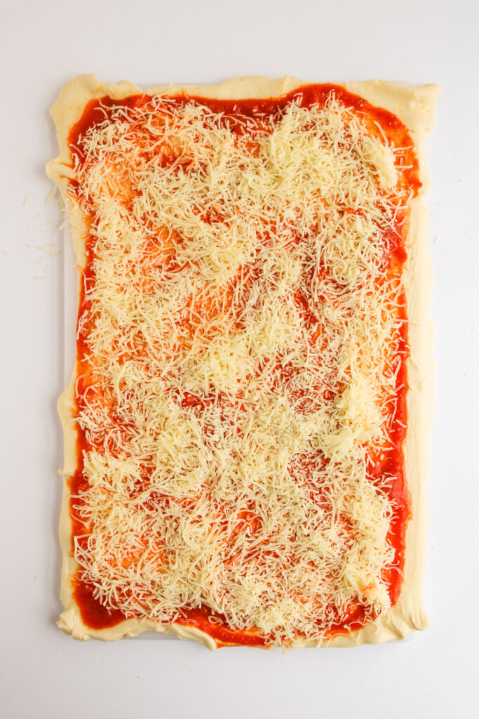 rectanbgle shaped dough with marinara and shredded mozzarella