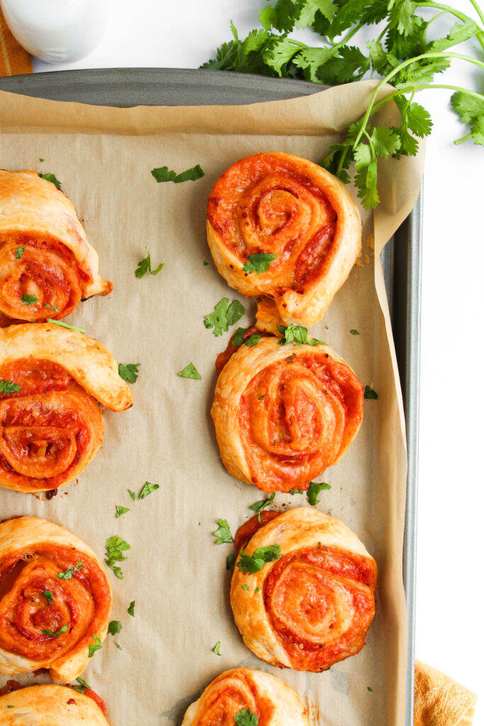 pizza pinwheels on parchment paper lined baking sheet