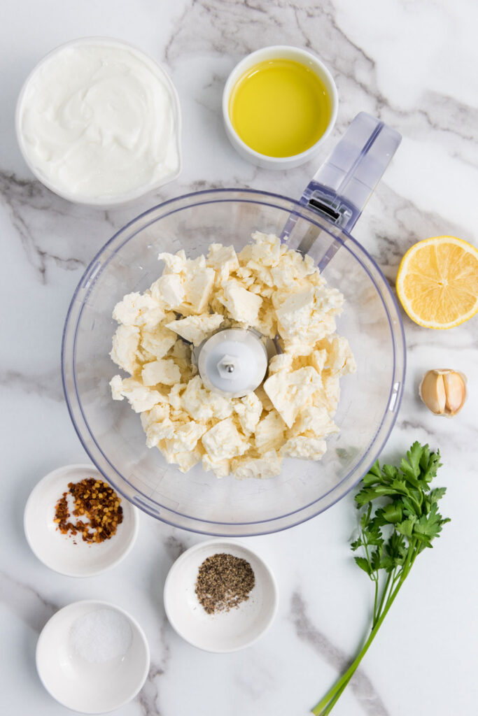 whipped feta dip ingredients in bowls around food processor with feta in it