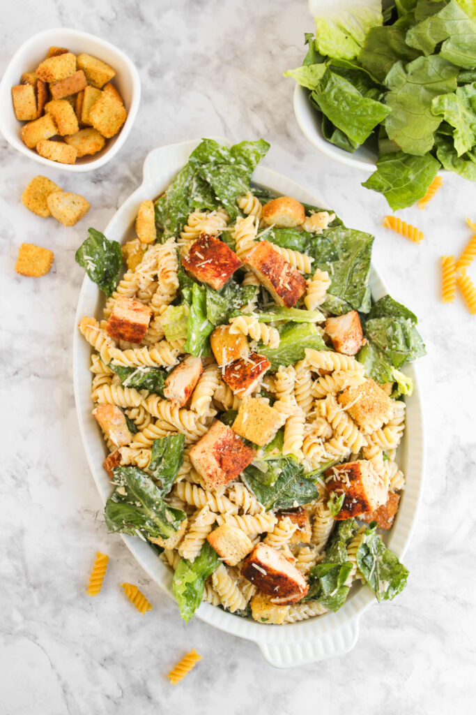overhead view of chicken caesar pasta salad in white serving dish