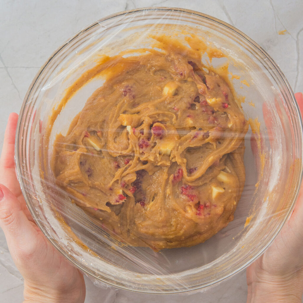White Chocolate Raspberry Cookies dough in glass bowl coverd with cling wrap