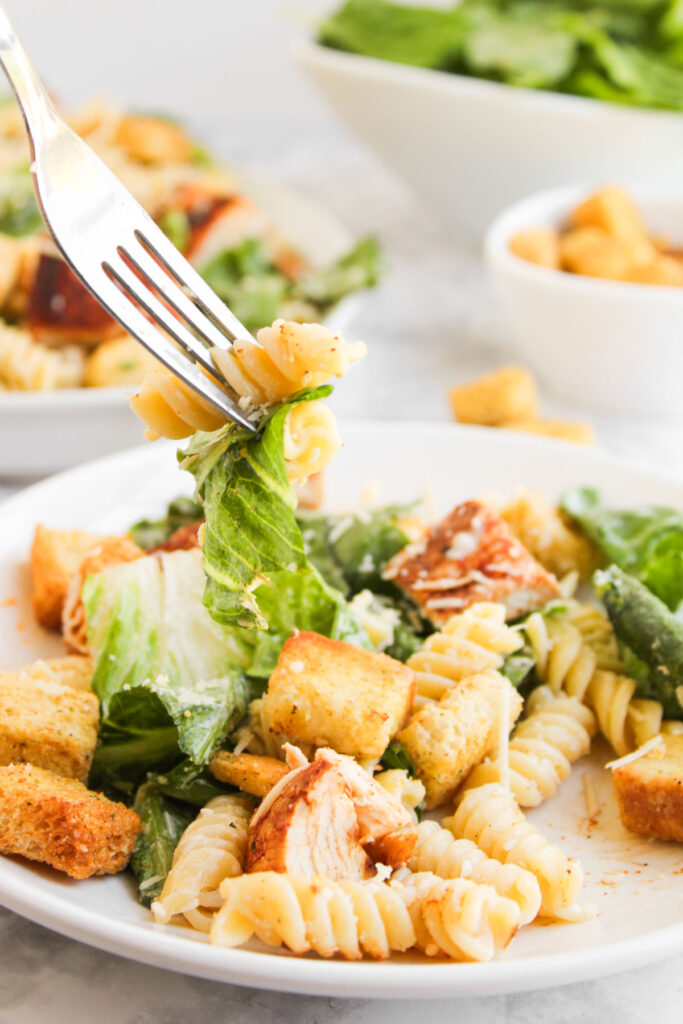 fork picking up bite of chicken caesar pasta salad