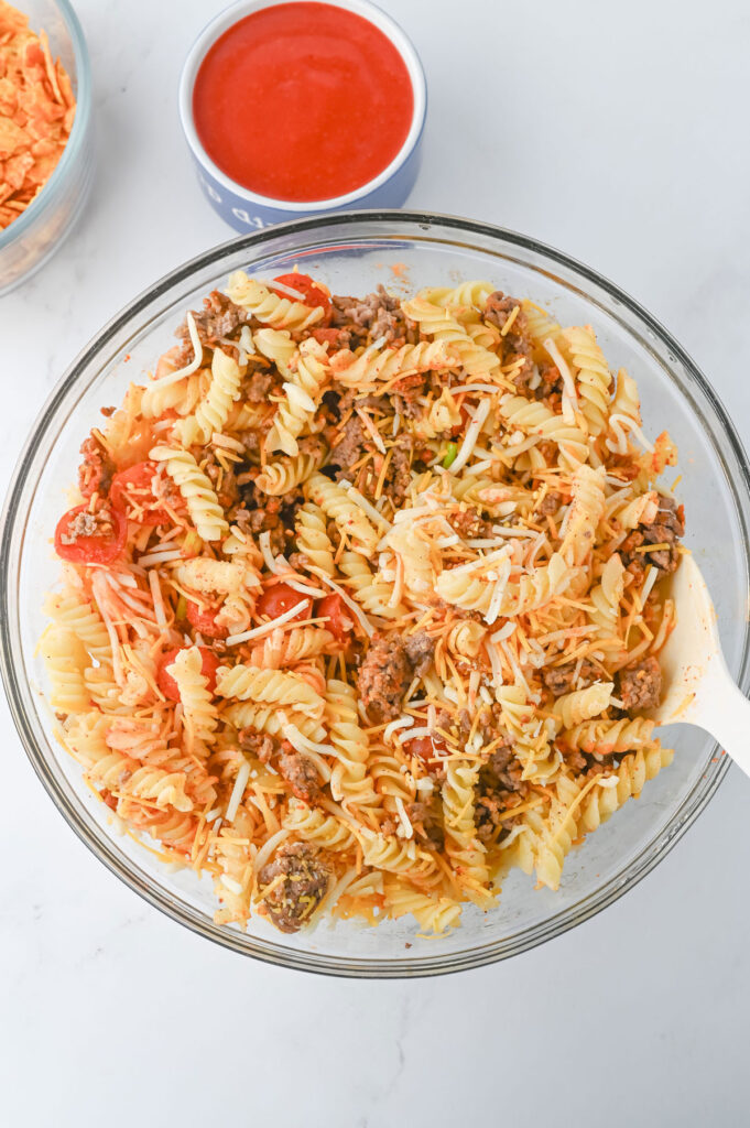 making taco pasta salad in glass bowl